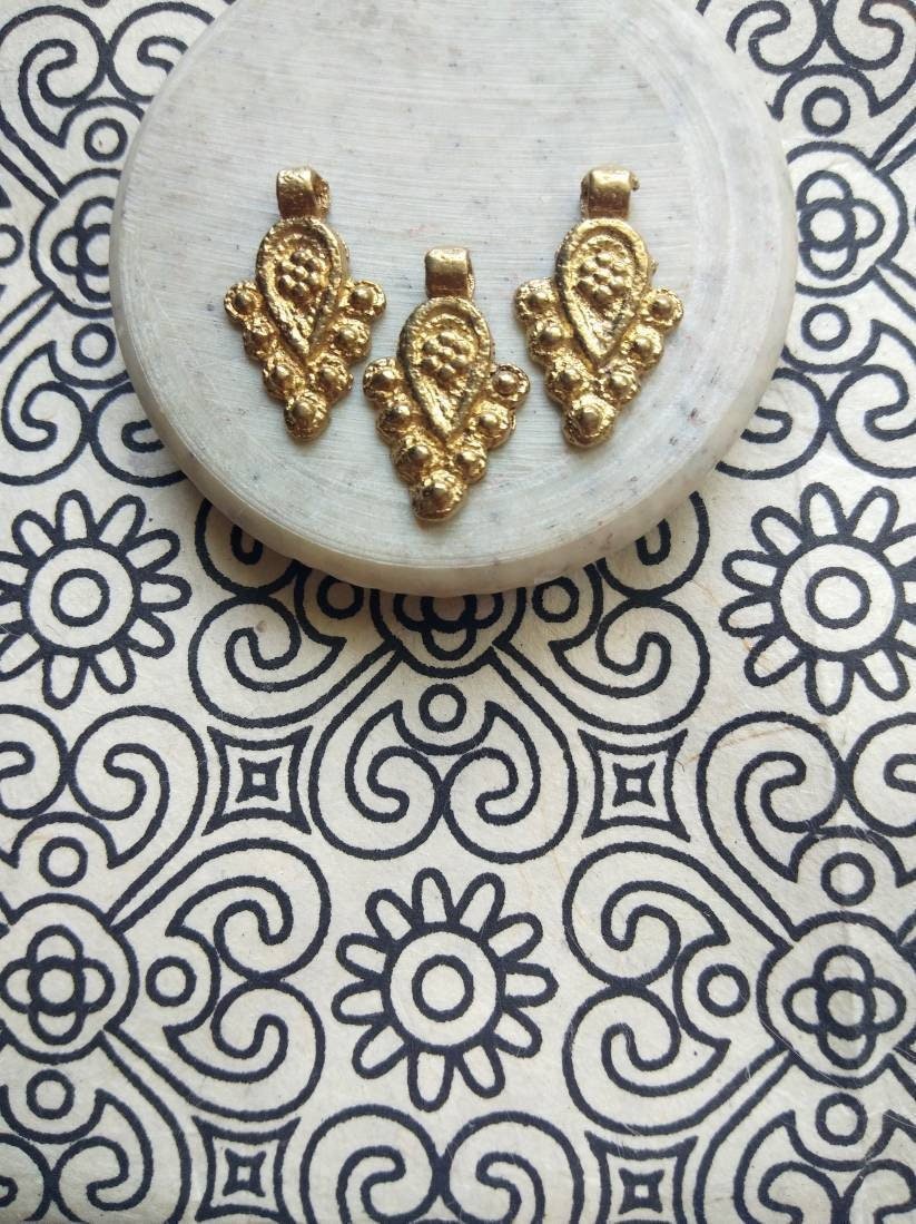 brass jewelry charms – Shop now: Close-up of artisan-crafted charms with intricate detailing.